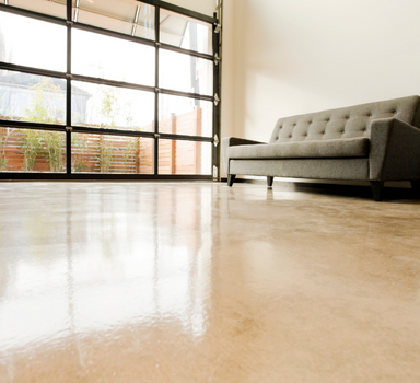 garage door with window panes next to a grey couch that rests on tan epoxy floors