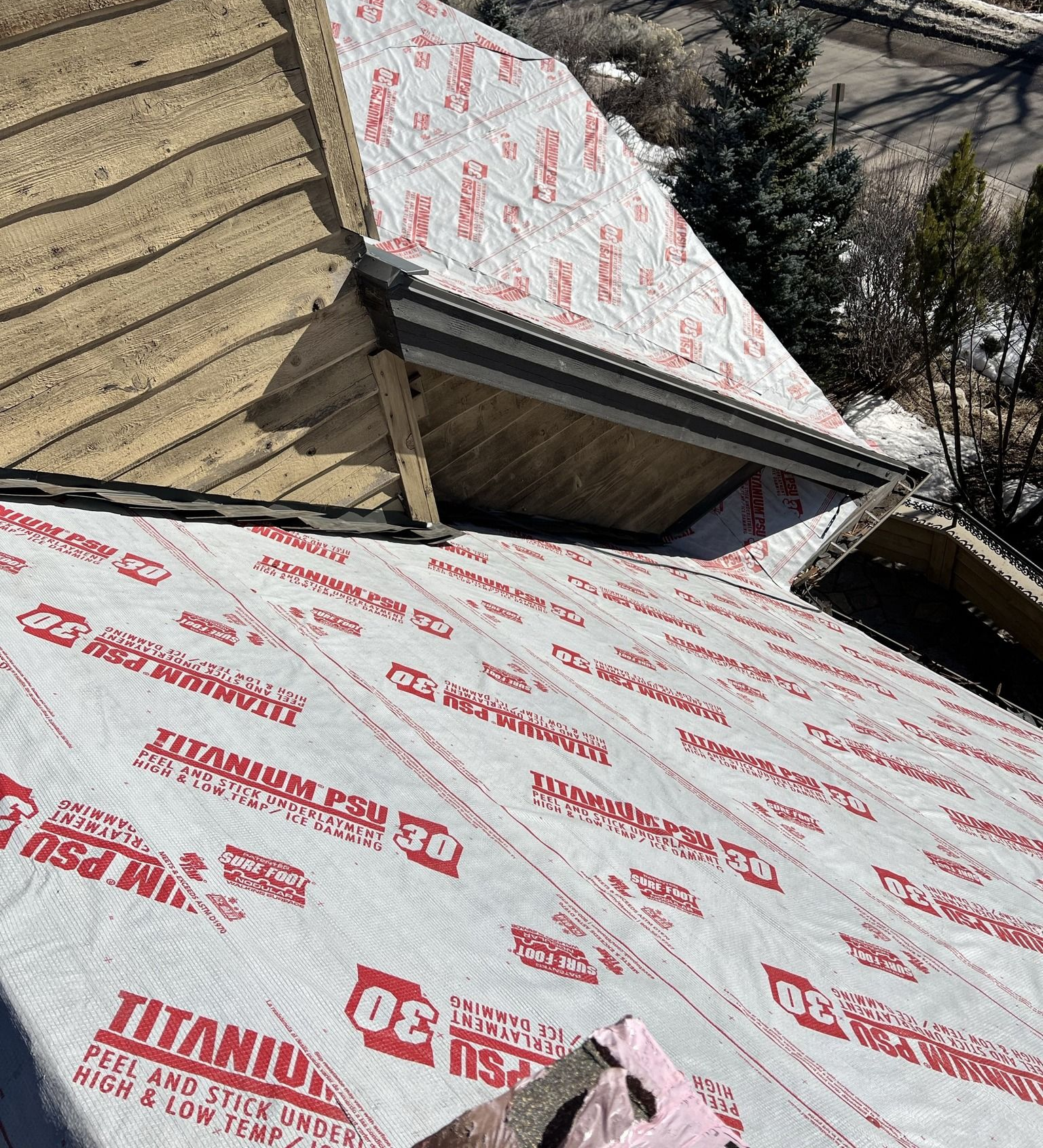 Roof under construction with white protective membrane and red branding on sloped sections