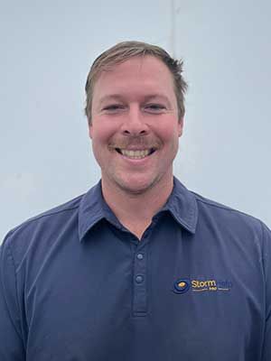 Smiling man in a blue polo shirt against a plain light background.