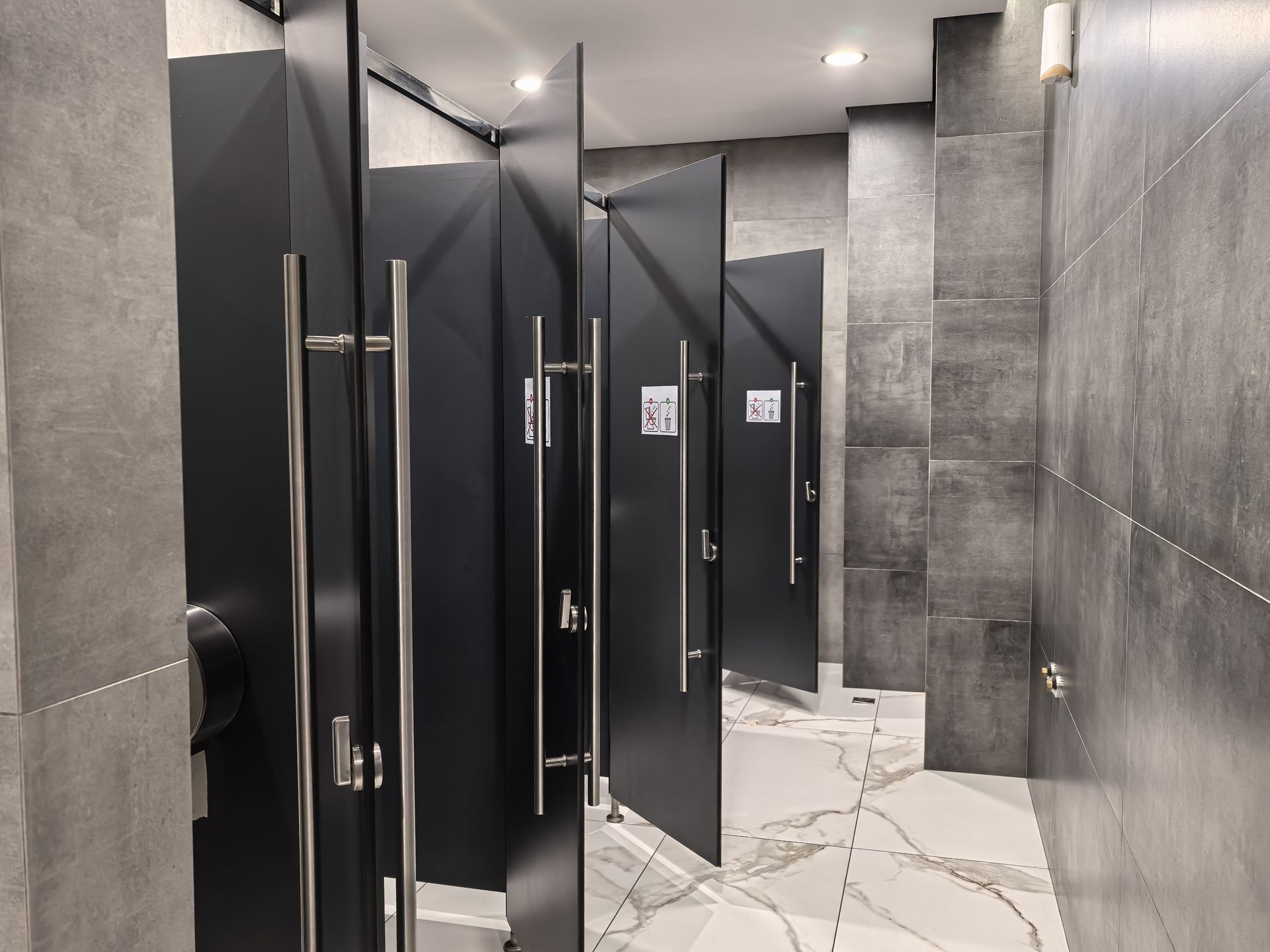 View of a fully renovated commercial bathroom with black doors.