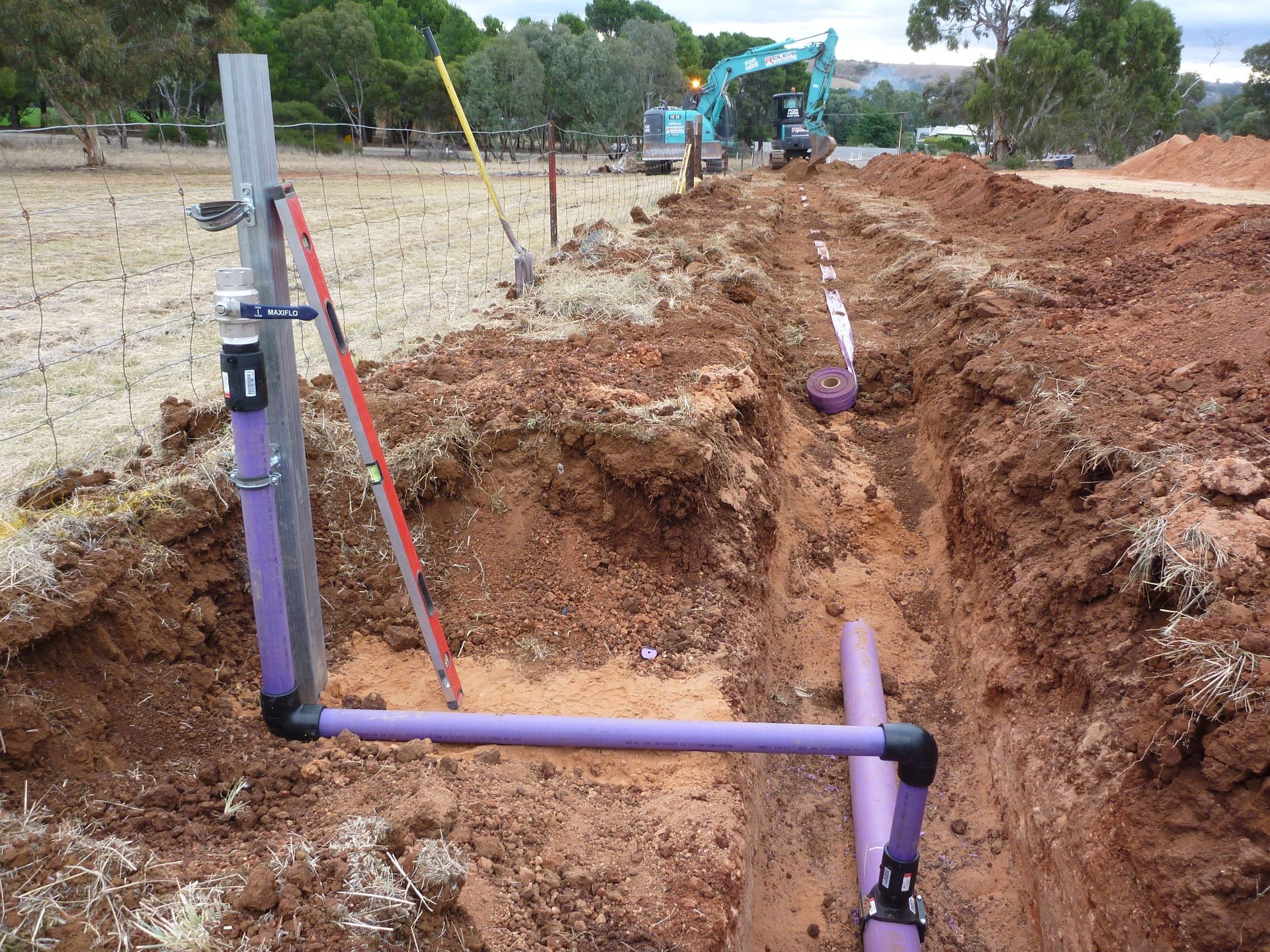 A purple pipe is laying in the dirt next to a fence | Murray Bridge, SA | Ridleys SA