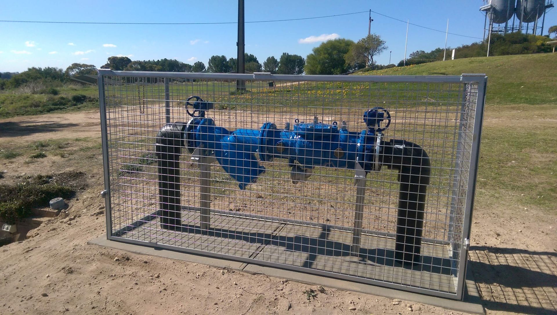 a metal fence surrounds a row of blue pipes