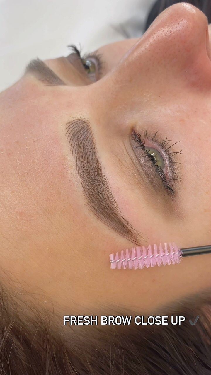 Close-up of a shaped eyebrow being brushed with a pink spoolie brush
