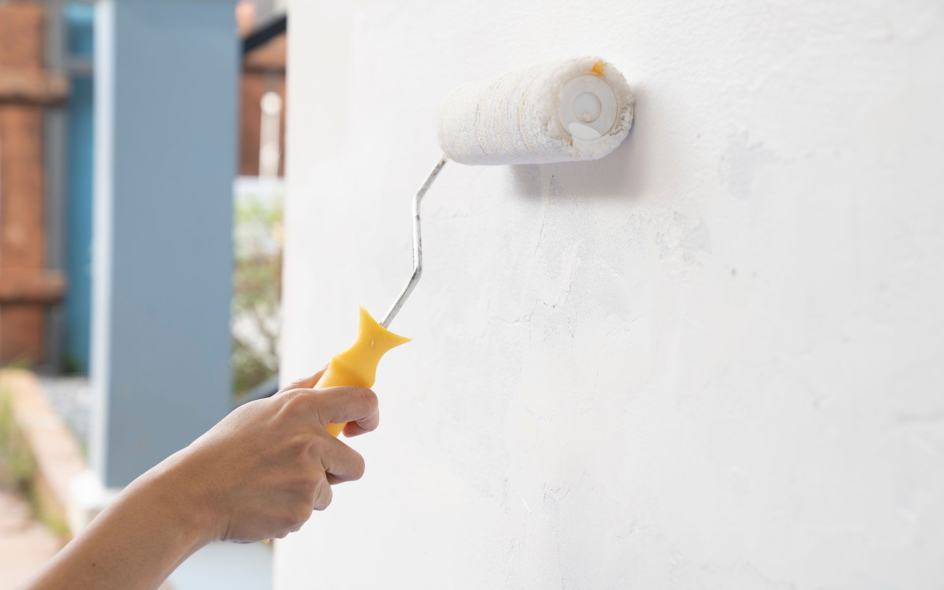 A person is painting a wall with a paint roller.