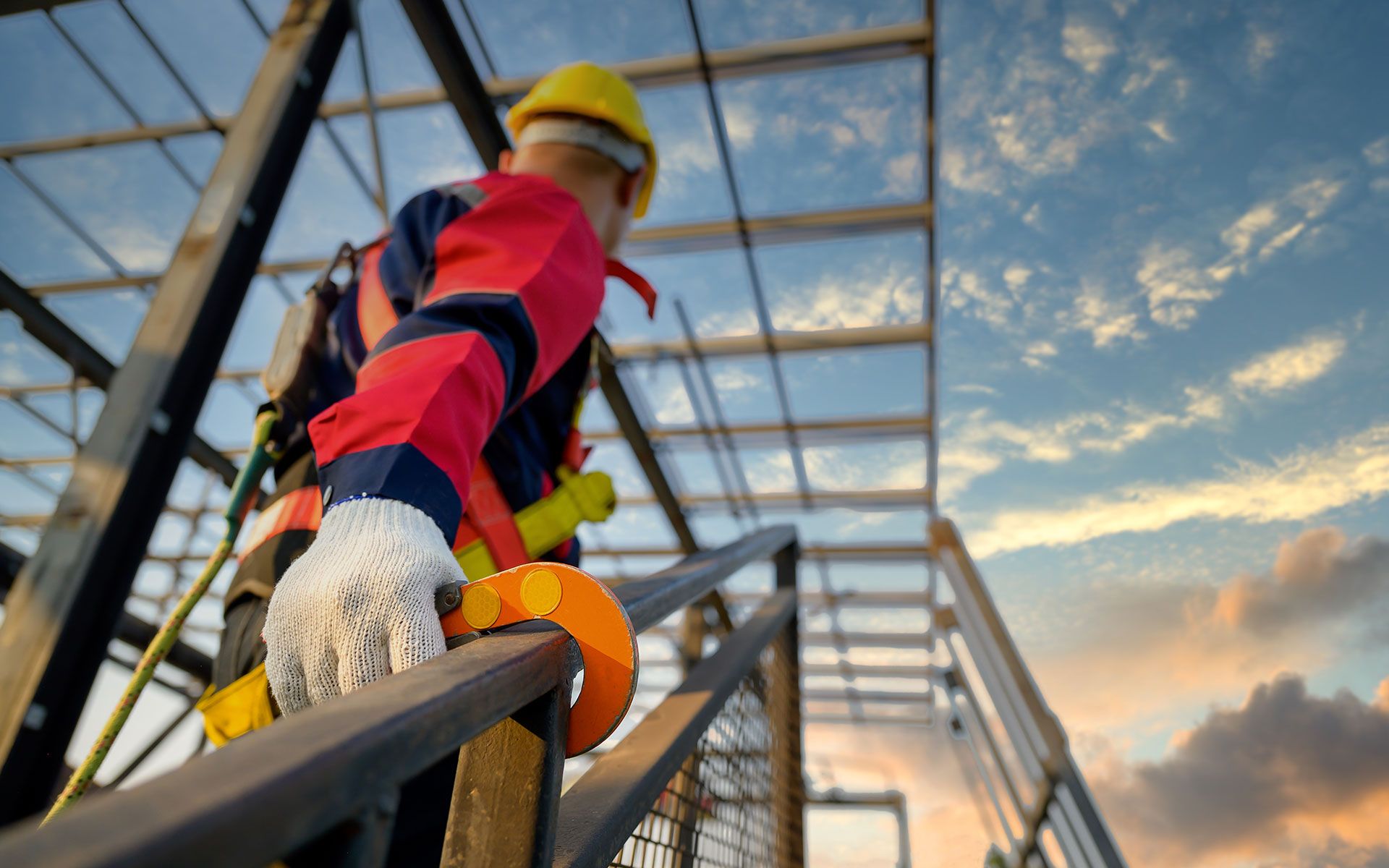 A construction worker is climbing a metal structure on a construction site.
