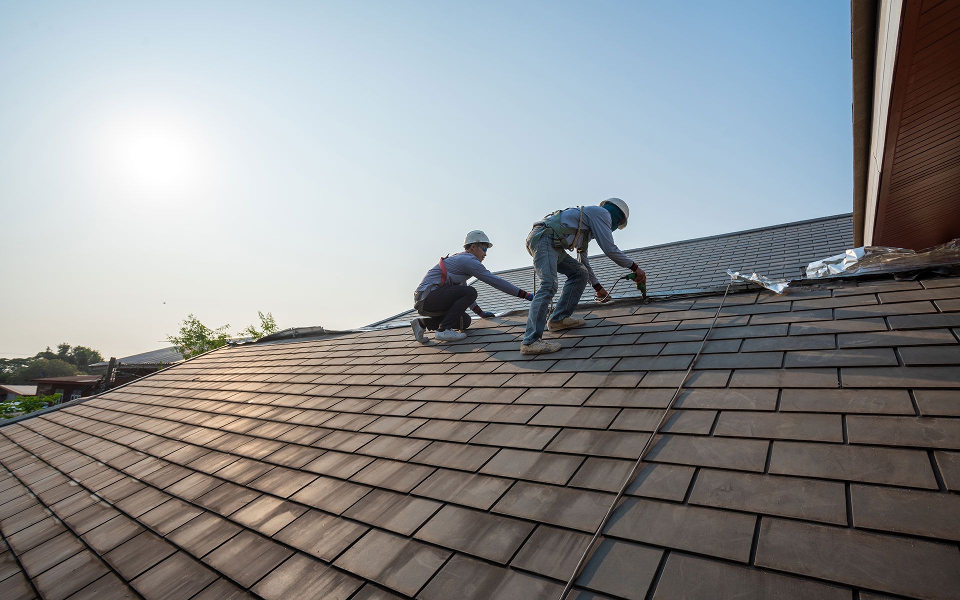 Two men are working on the roof of a house.
