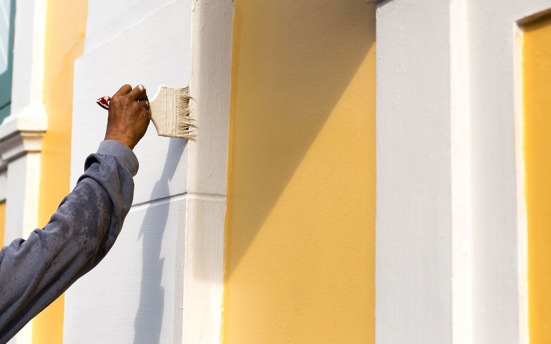 A man is painting the side of a building with a brush.