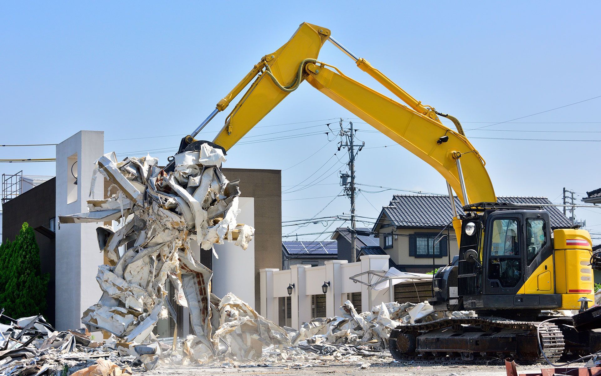 A large yellow excavator is demolishing a building.