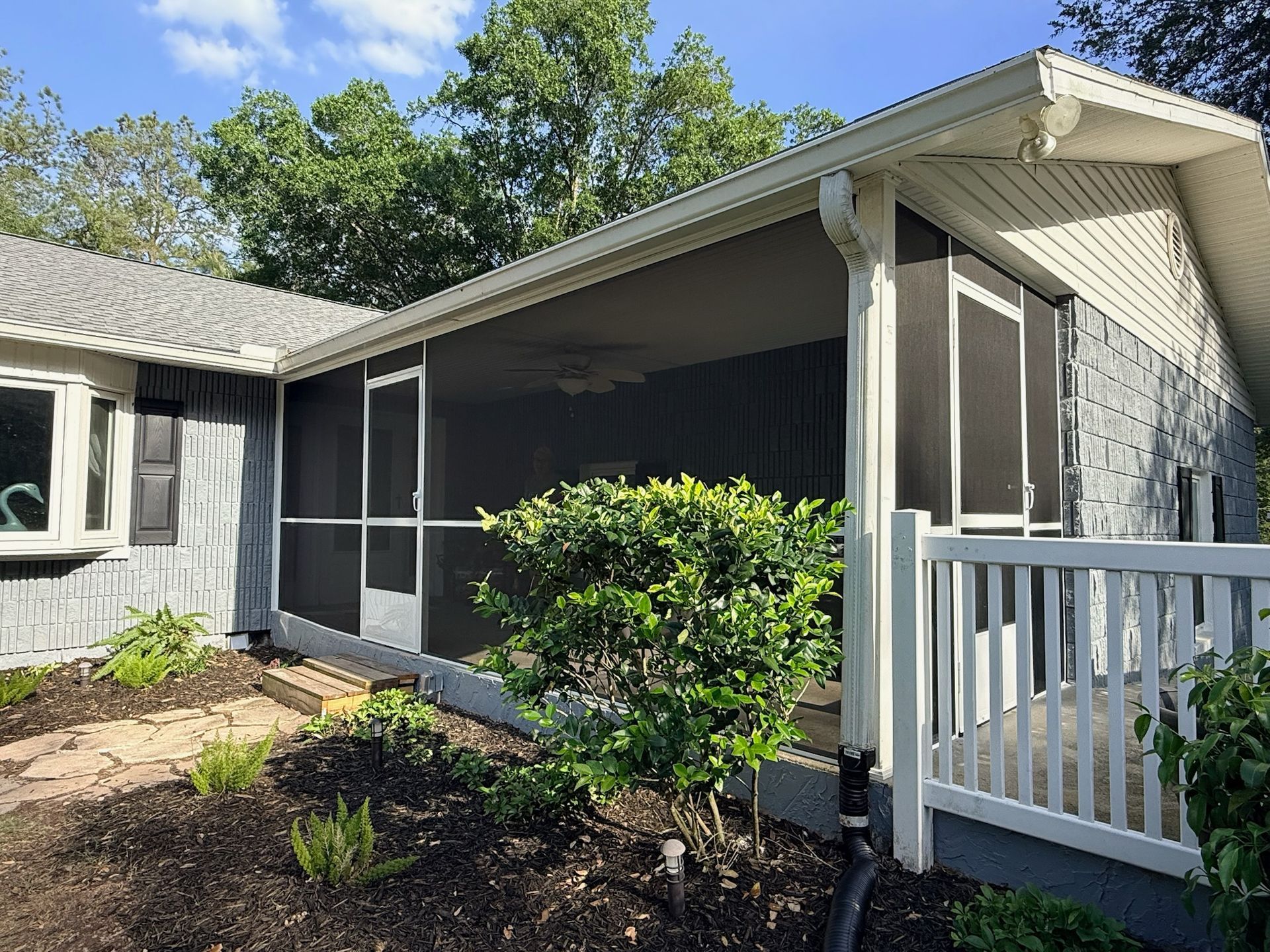 Screened in front porch on grey house with white rails