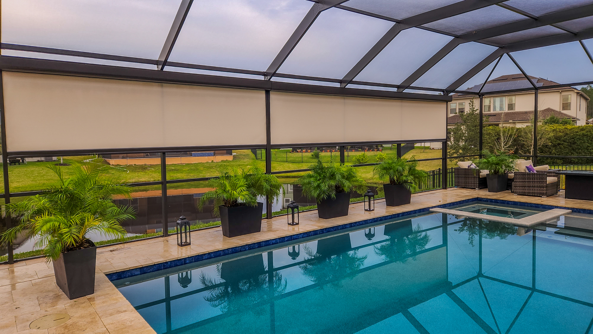 Covered backyard pool with potted plants and seating under a screened patio
