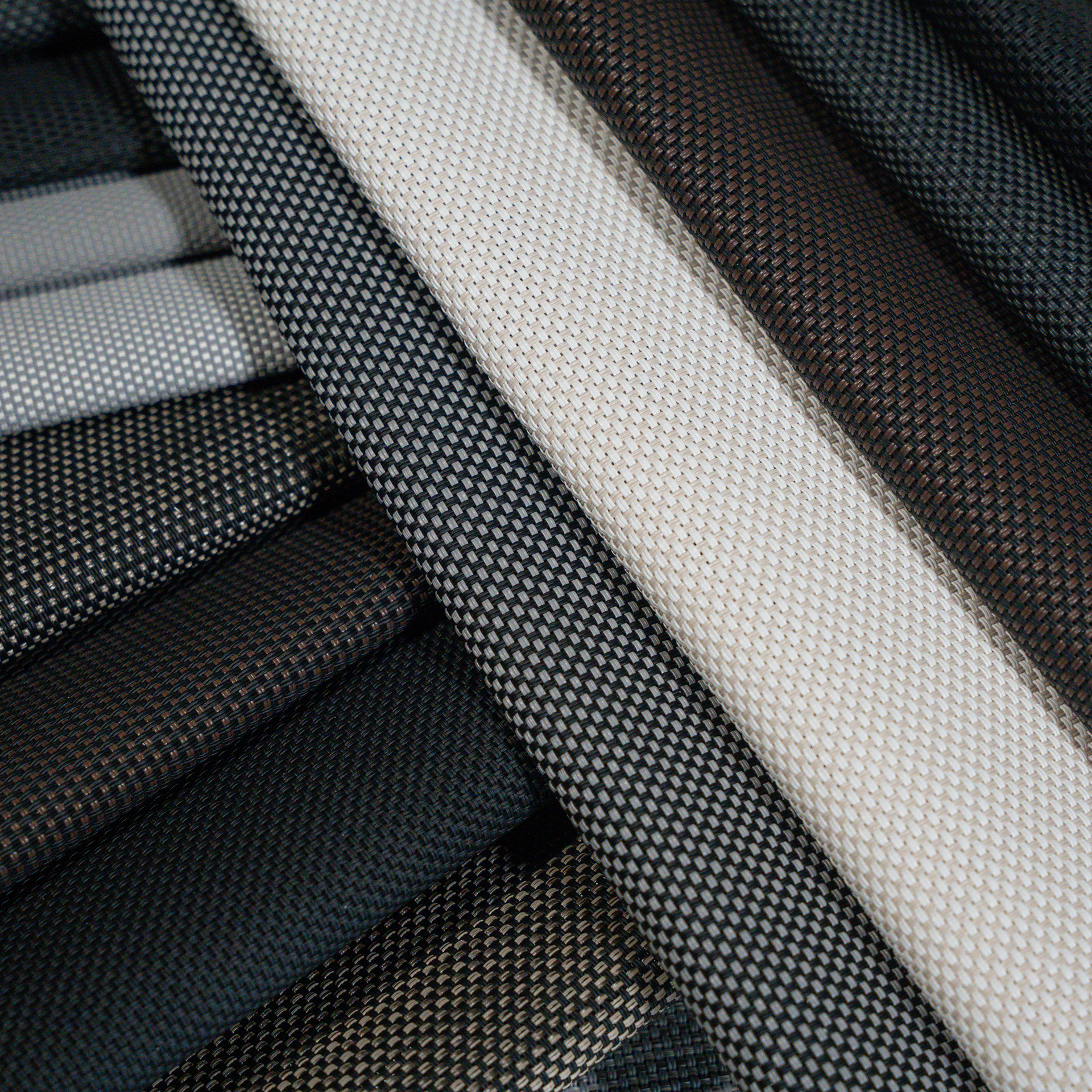 Folded black, gray, and white fabric rolls stacked diagonally in a close-up view