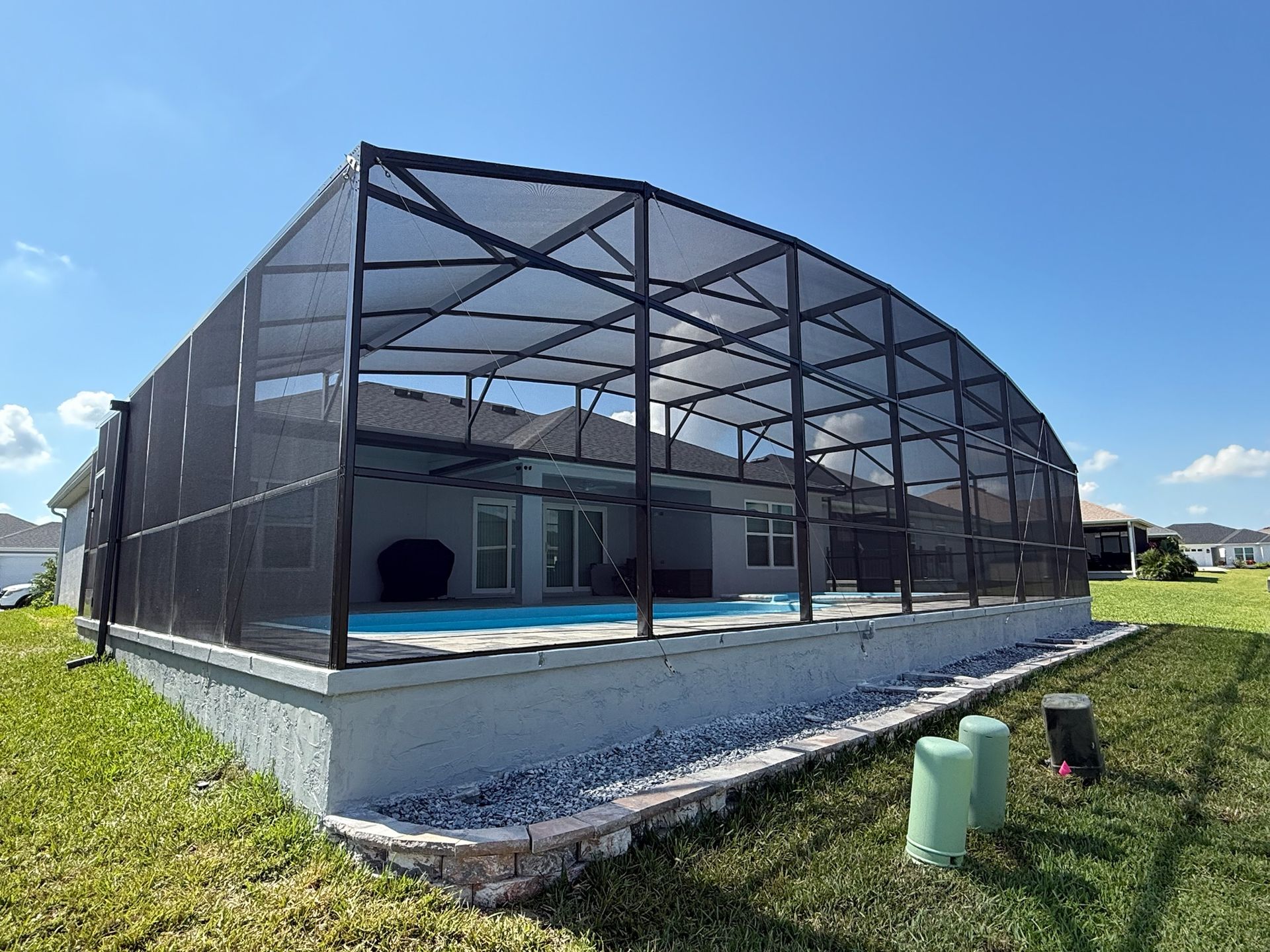 Screened indoor pool with blue water and attached hot tub under a glass ceiling.