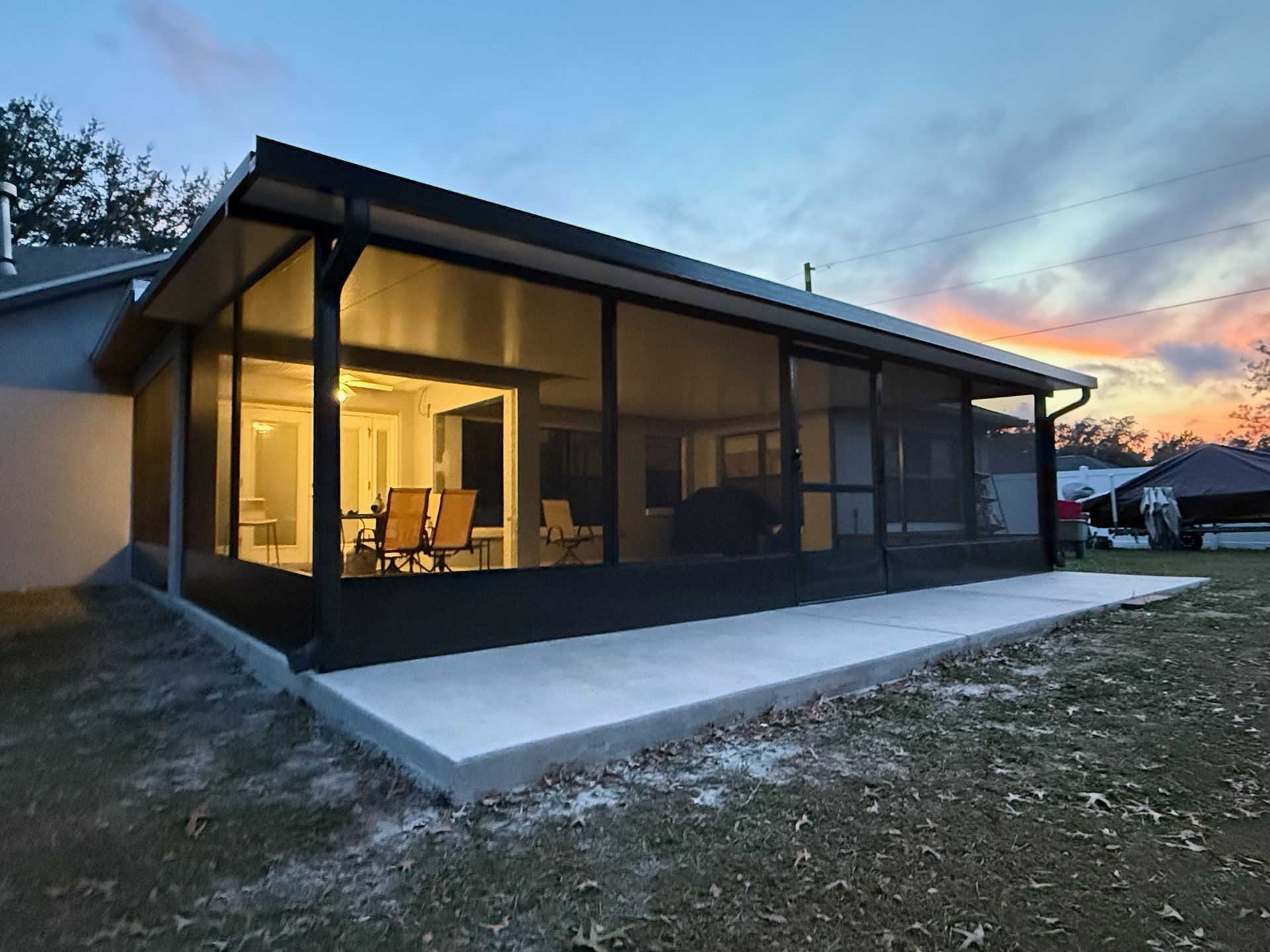 Modern black house with large glass walls and warm interior lights at dusk