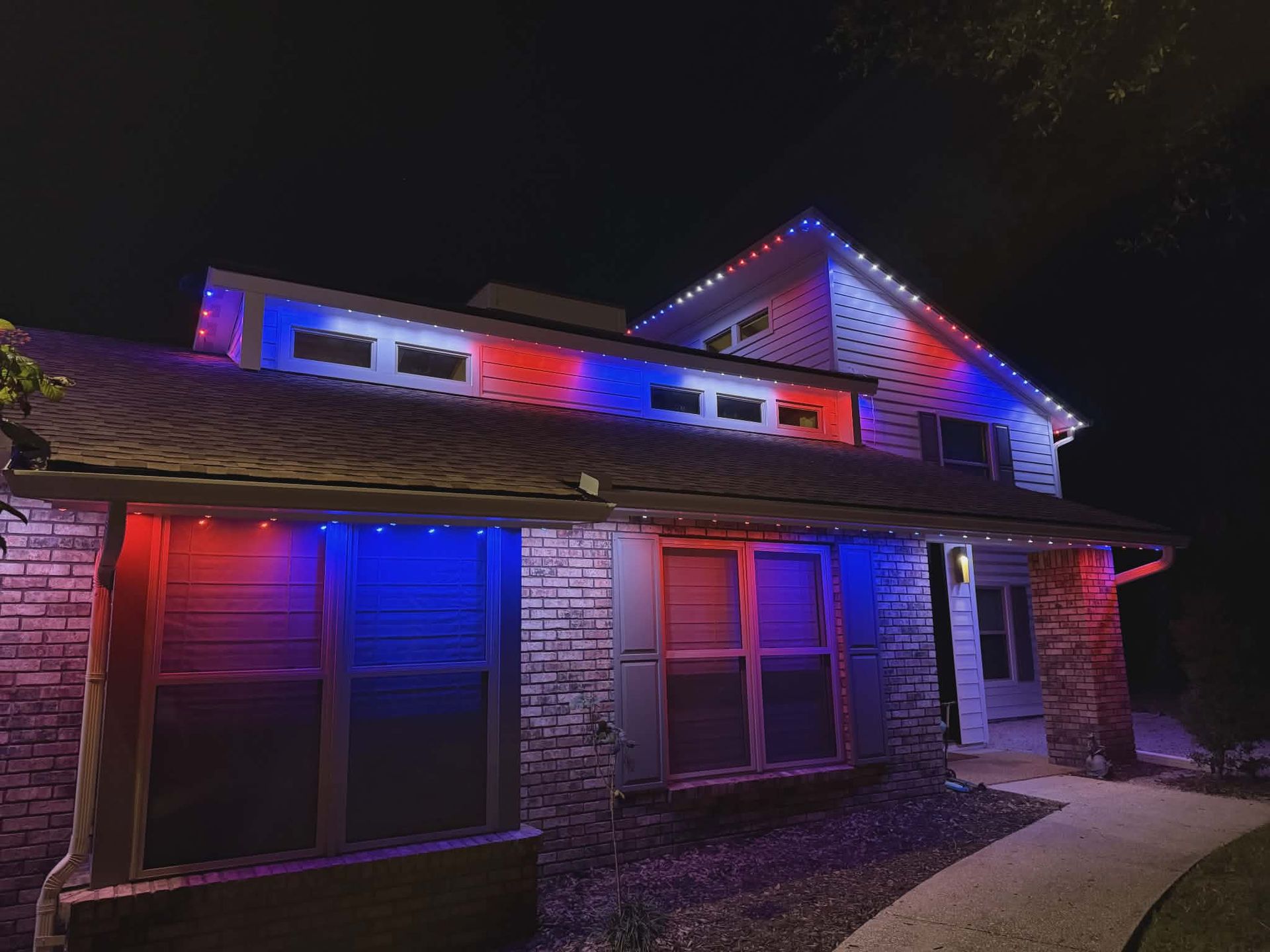 House illuminated at night with red and blue lights, possibly for patriotic display.