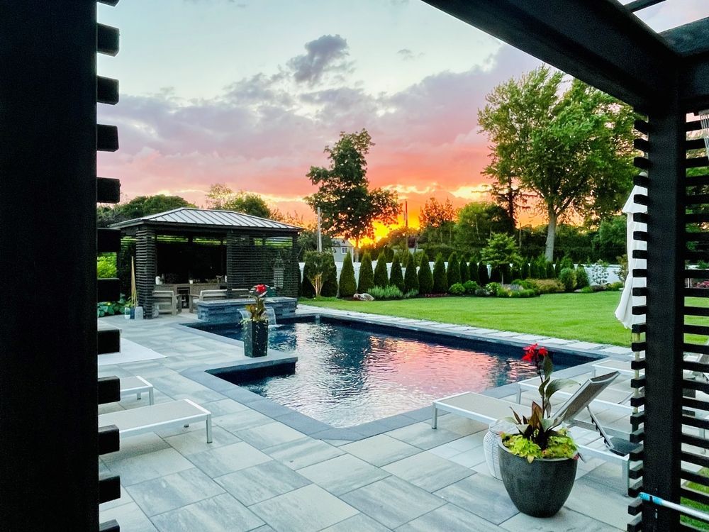 A large swimming pool in a backyard with a sunset in the background.