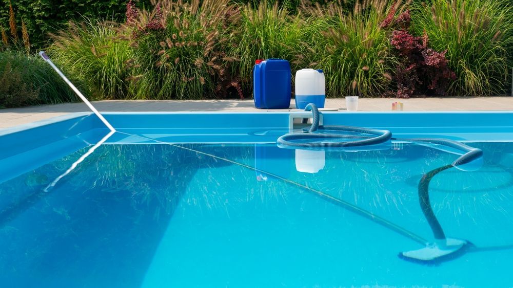 A swimming pool is being cleaned with a vacuum cleaner.