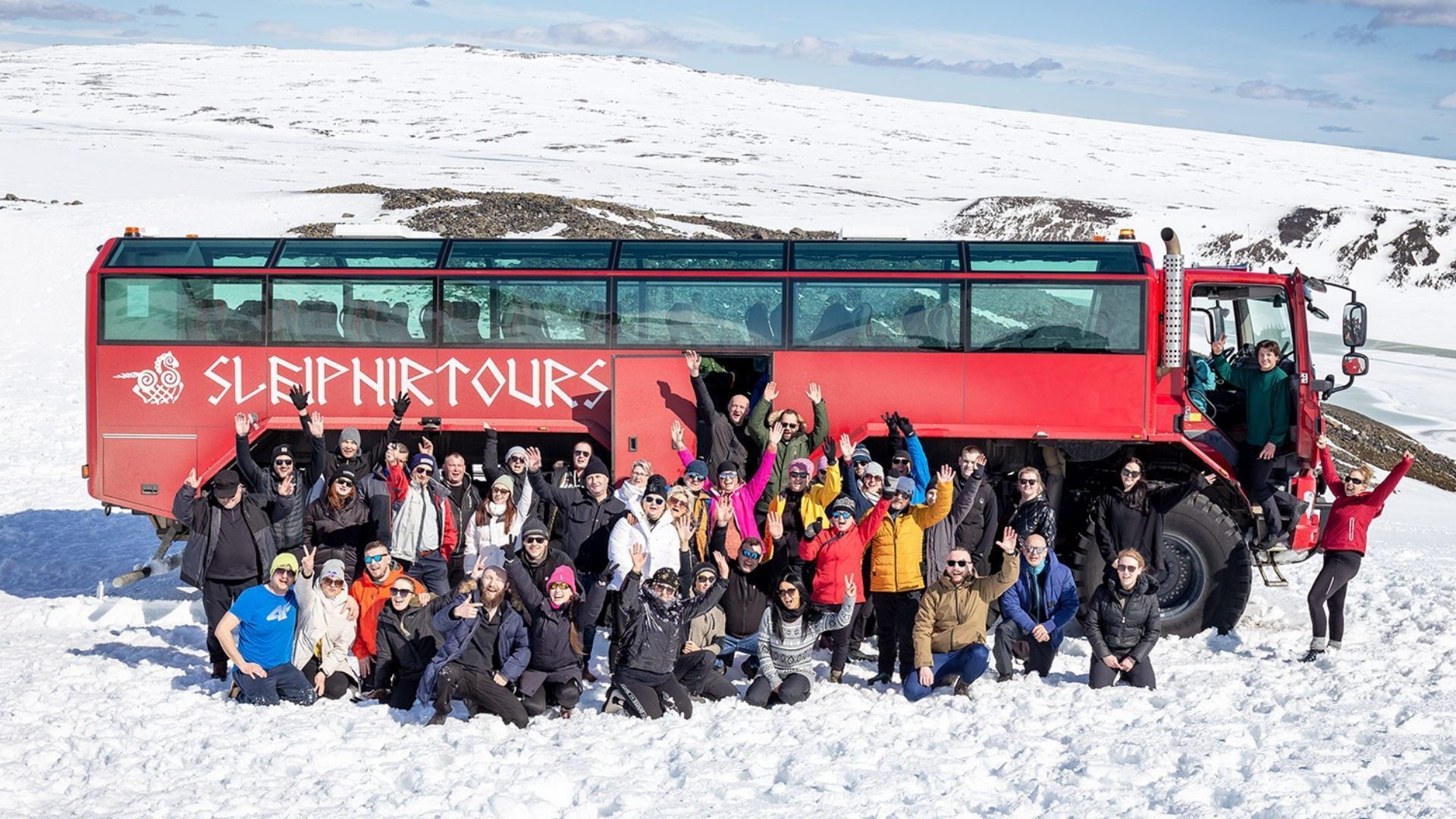 Happy group in front of the Monster truck on the snowy glacier