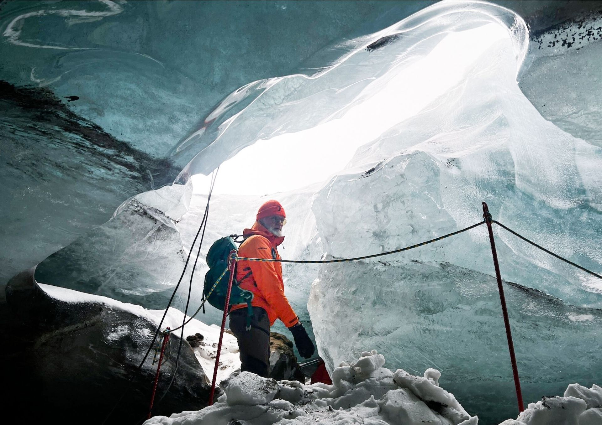 A man standing in the Neptune natural ice cave, winter 2025 to 2026, marveling at the blue ice