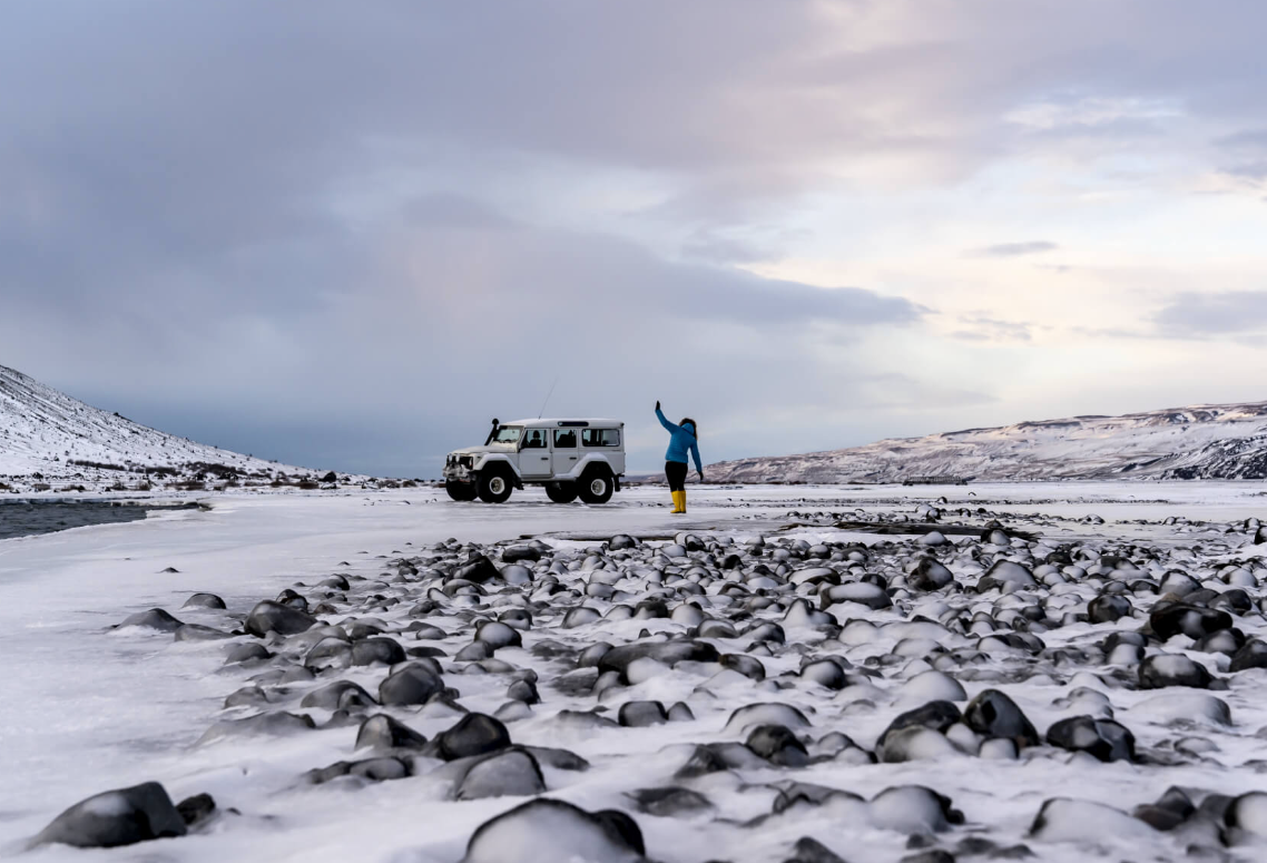 person standing in front of the car in an winter landscape