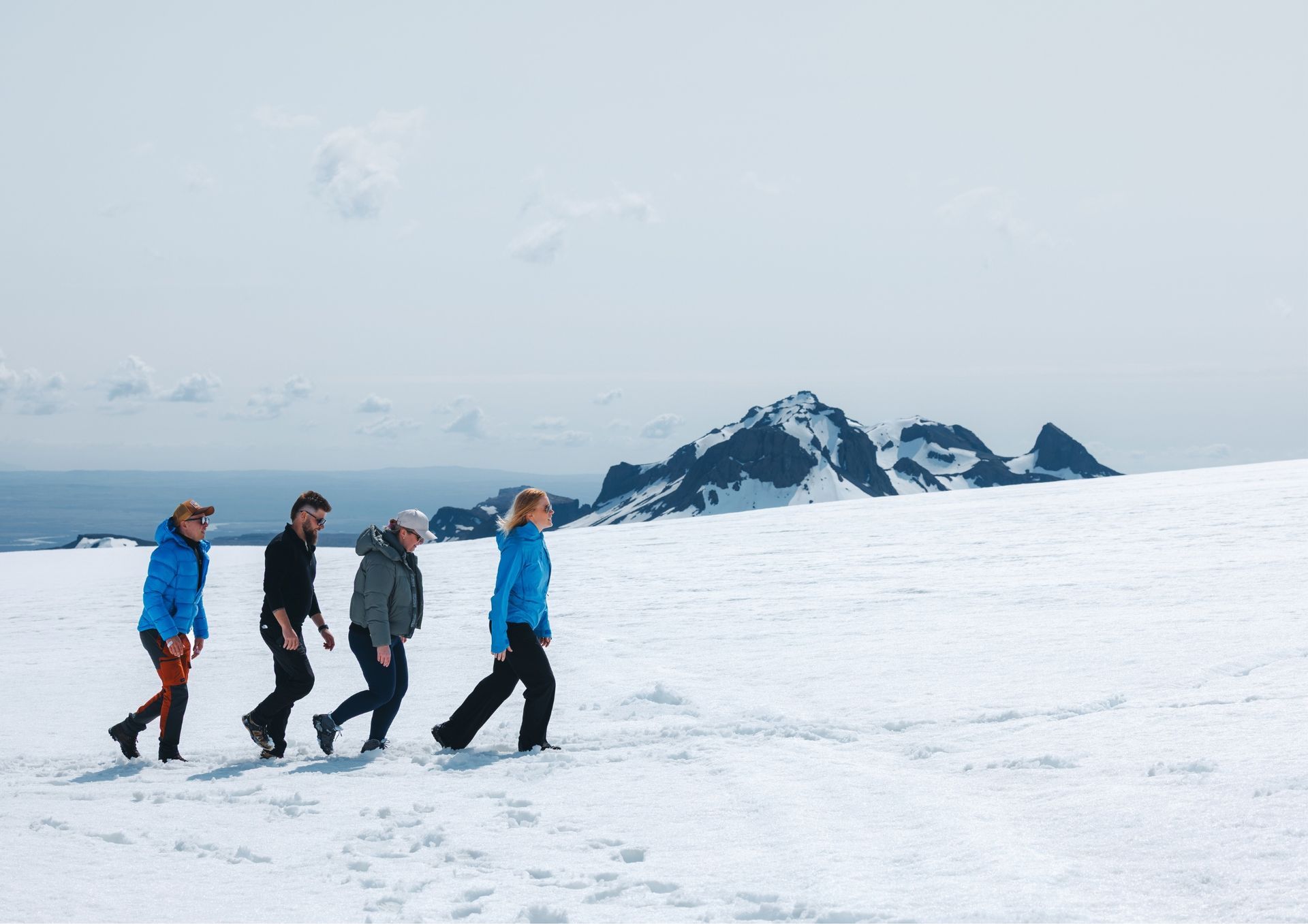 Happy guests walking in the snow on Langjökull Glacier during the Sleipnir Monster truck tour.