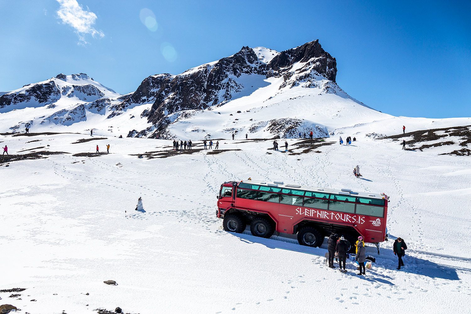 a photo of a red monster truck on top of a glacier