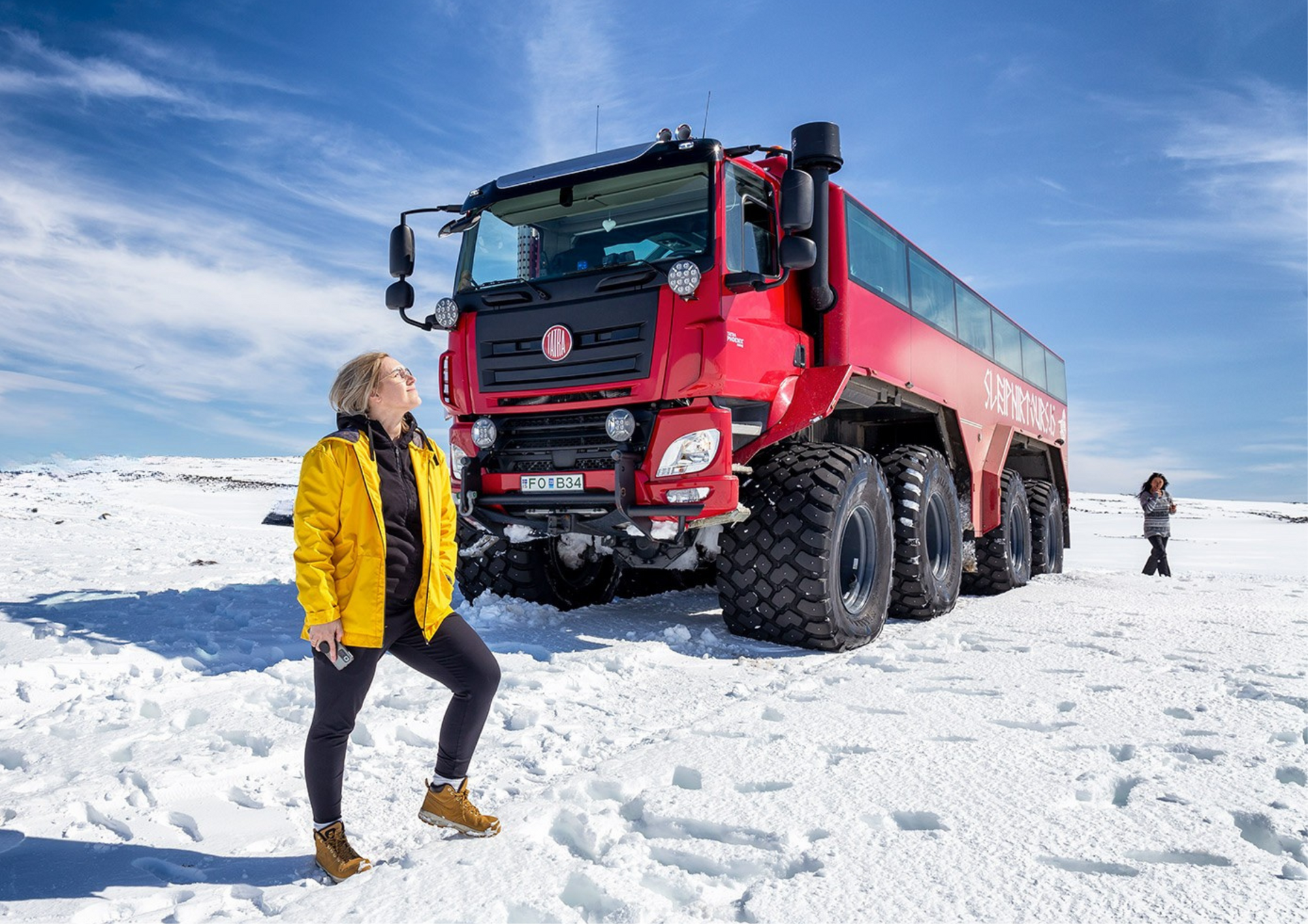Woman standing in front of the Monster truck enjoying the sun on the glacier