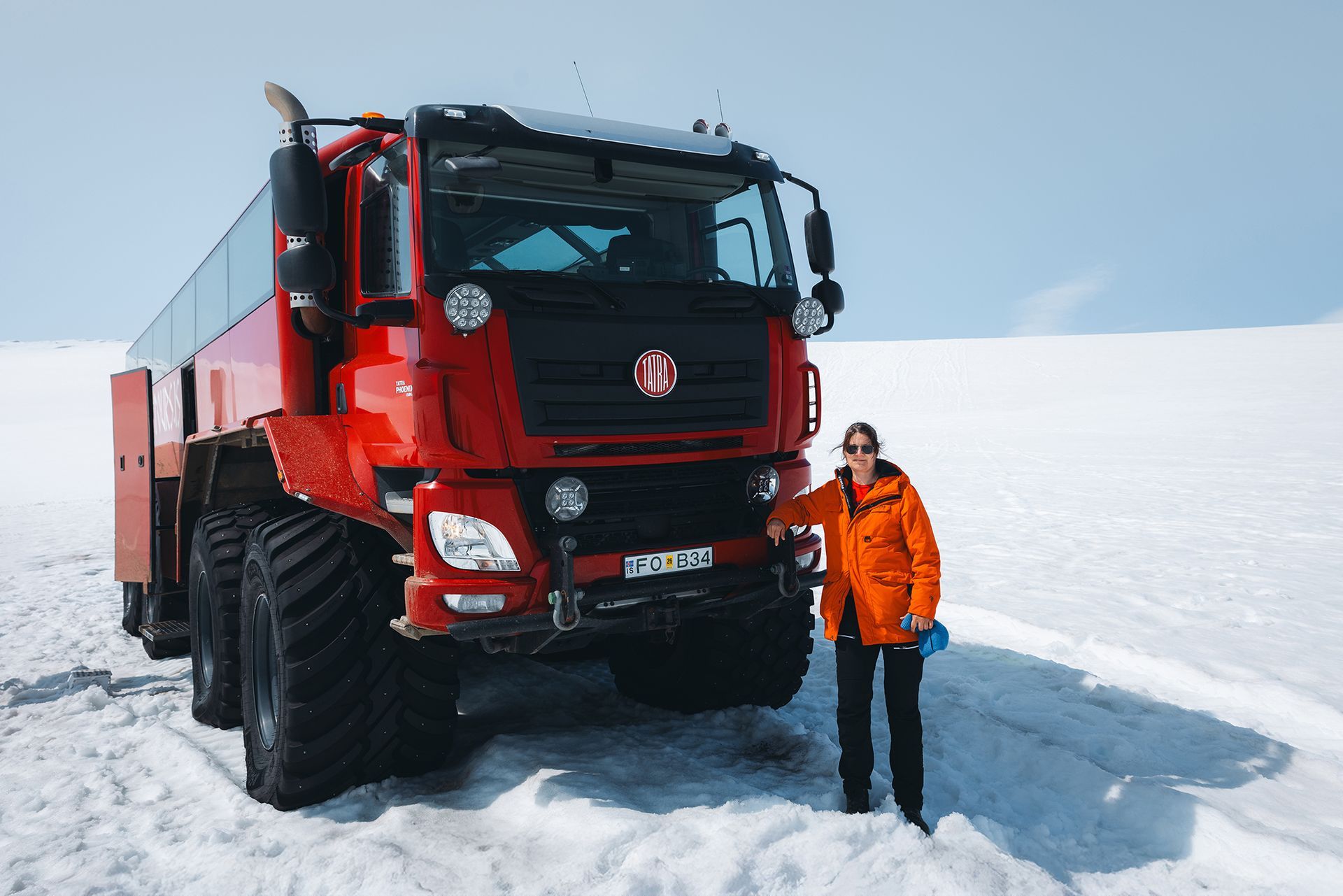 A person standing in front of the Sleipnir Monster truck, well dressed with a warm jacket