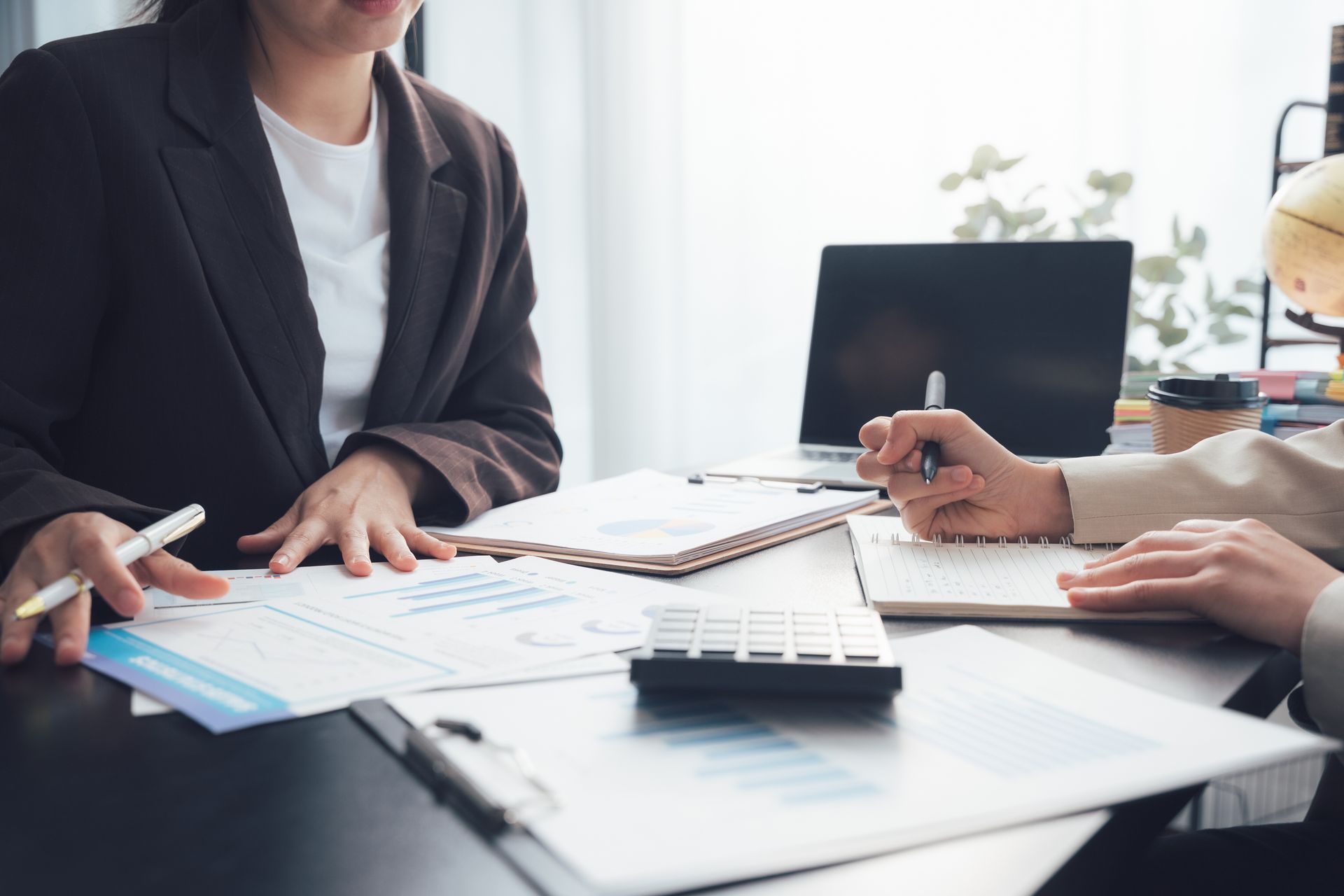 Two individuals engage in a consultation, reviewing documents for tax return preparation. Two individuals engage in a consultation, reviewing documents for tax return preparation.