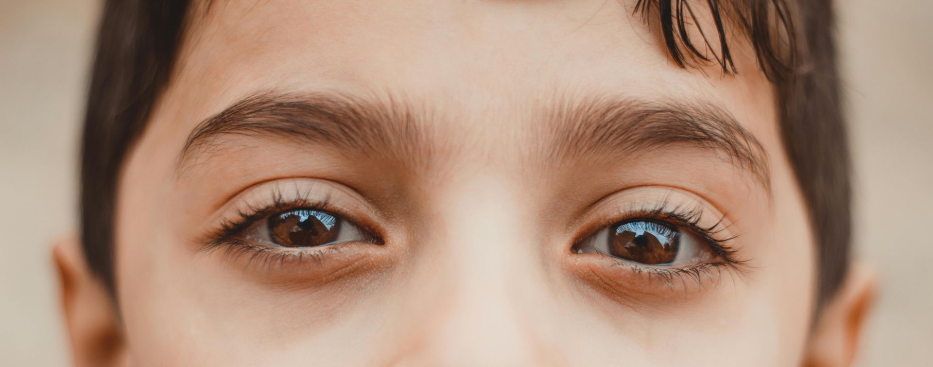 Close-up of a person's eyes, brown irises, dark eyebrows, and visible eyelashes.