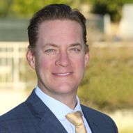 A man in a suit and tie is smiling for the camera.