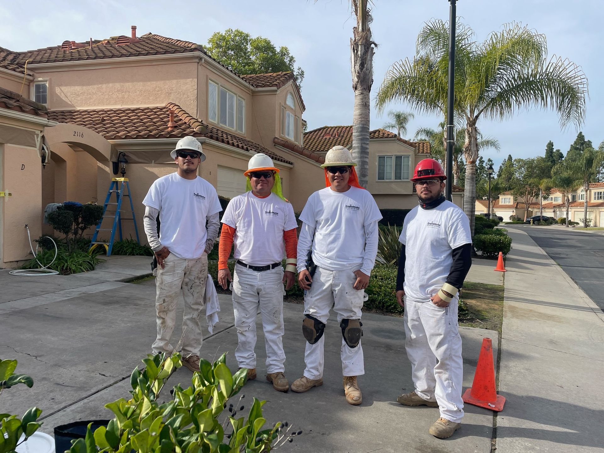 A group of men wearing hard hats are standing in front of a house.
