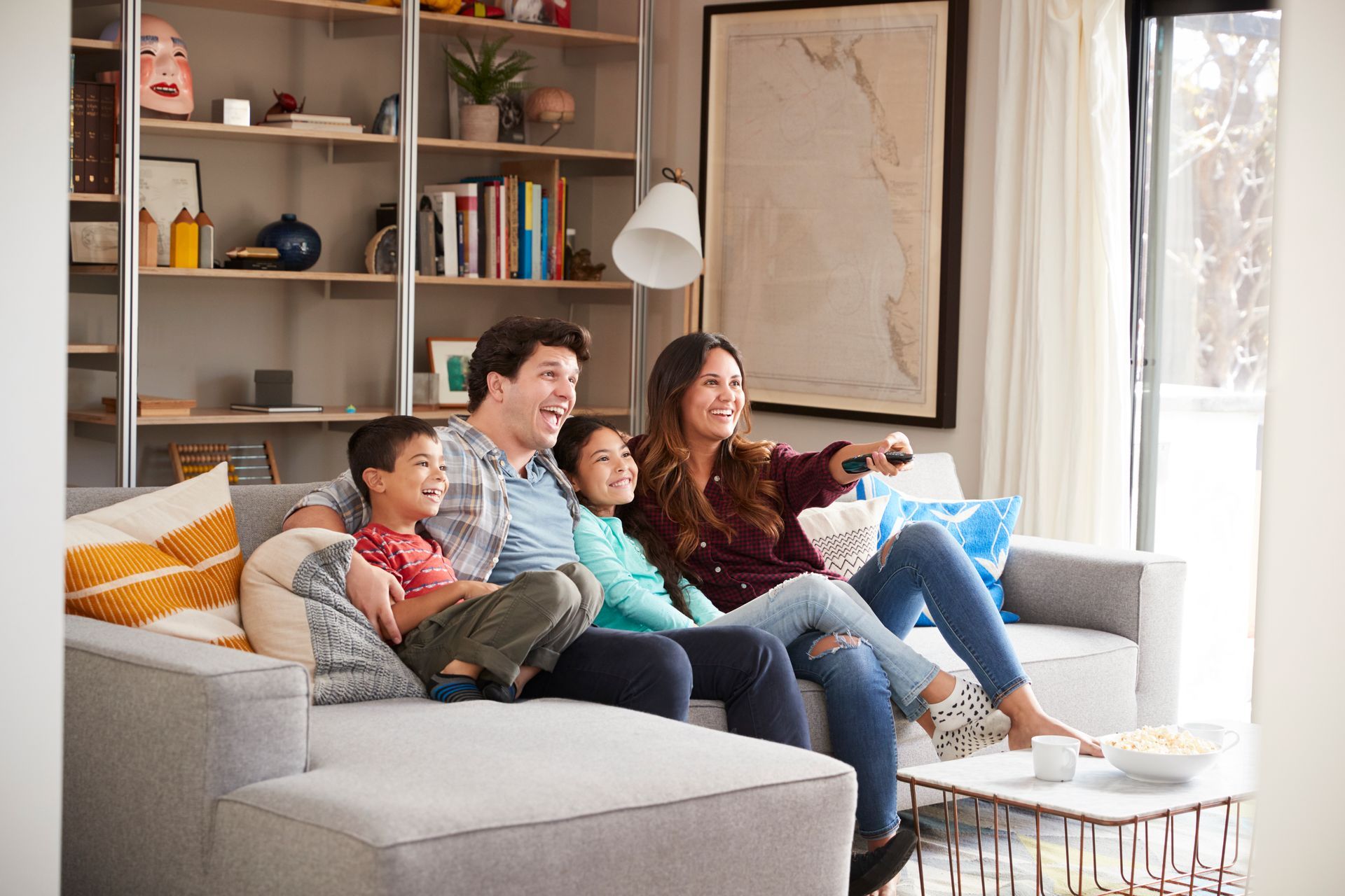 A family is sitting on a couch watching tv.