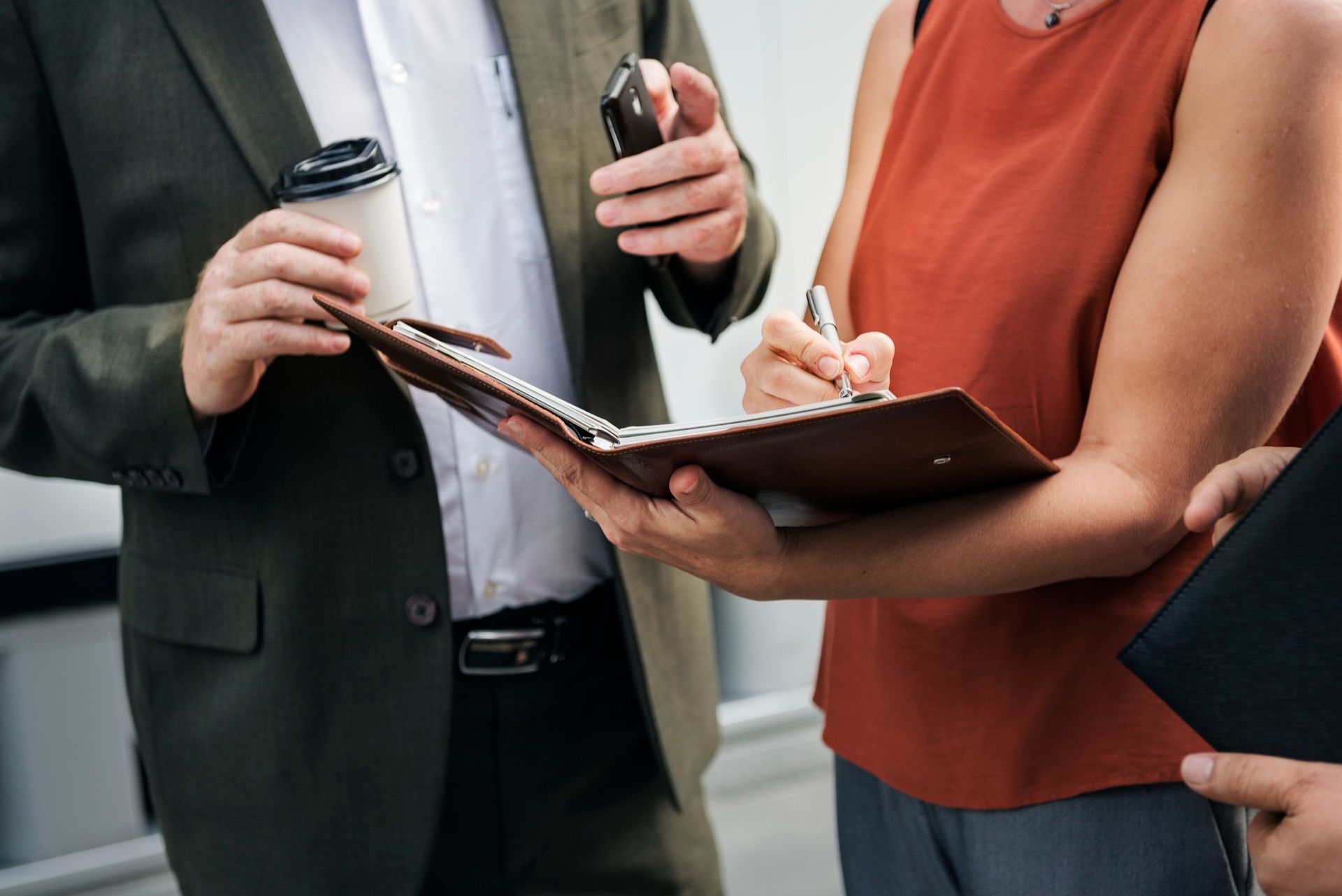 People in business attire discussing documents and taking notes at a meeting