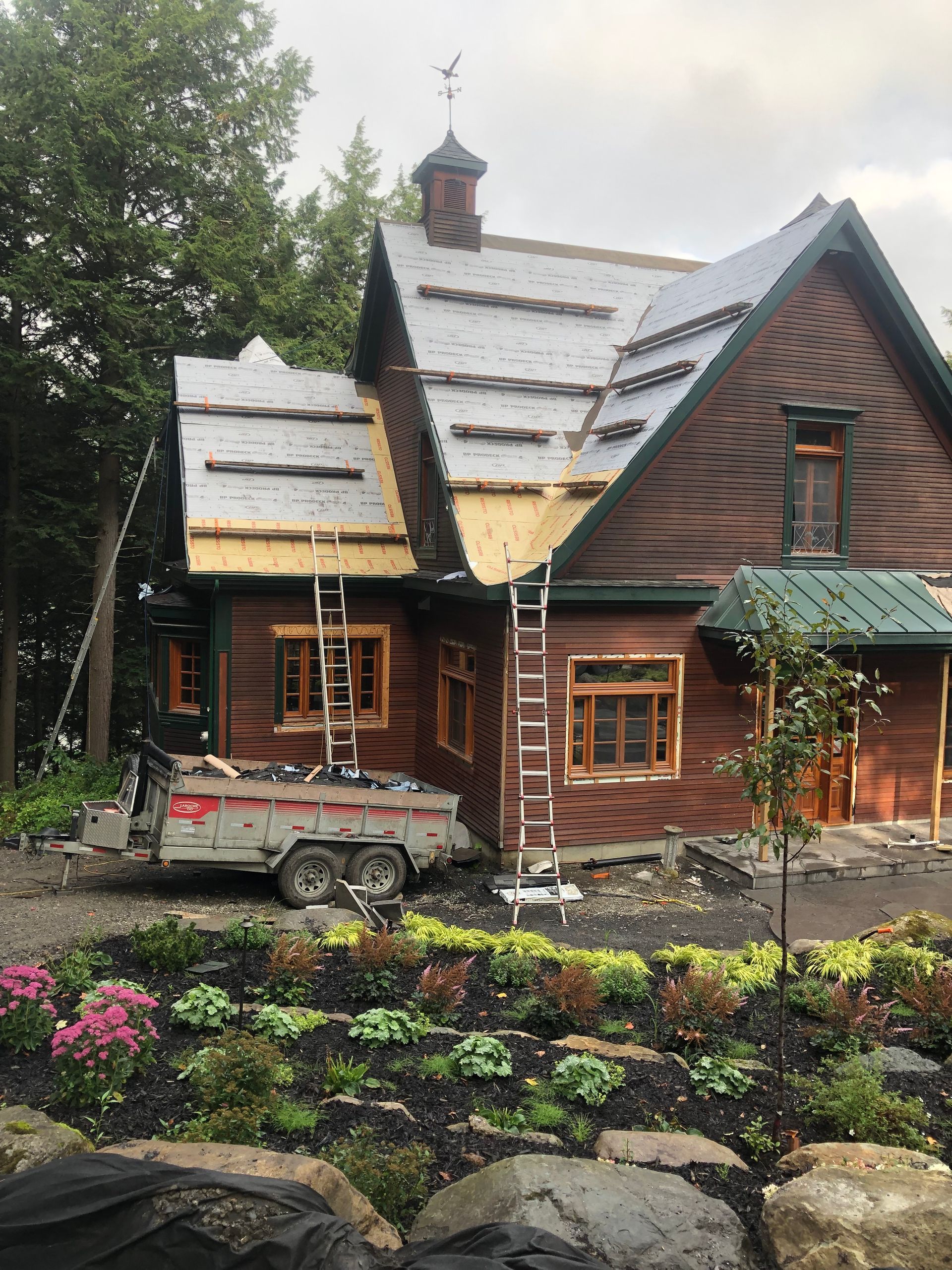 Une remorque est garée devant une maison en bois en construction.
