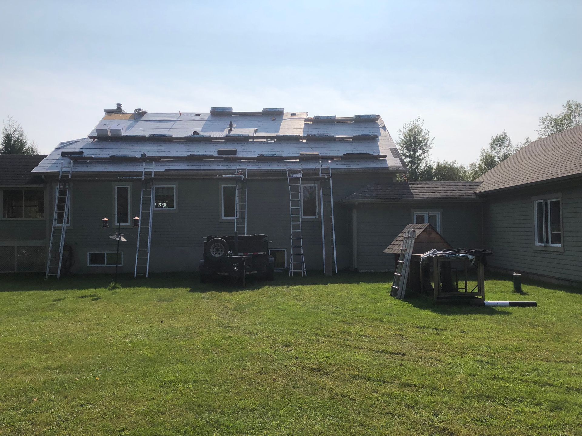 Une maison avec un toit qui est en train d'être installé par une journée ensoleillée.