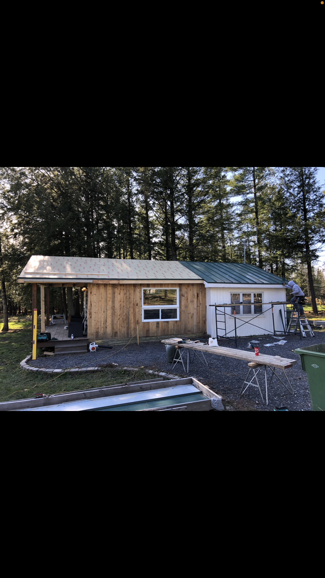 Une petite maison avec un toit vert est en construction dans les bois.