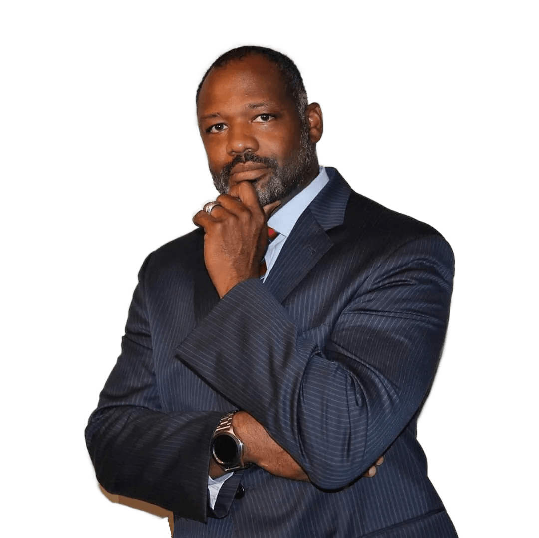Daniel R. Crumby in a blue suit and light blue shirt, posing with arms crossed and hand on their chin against white.