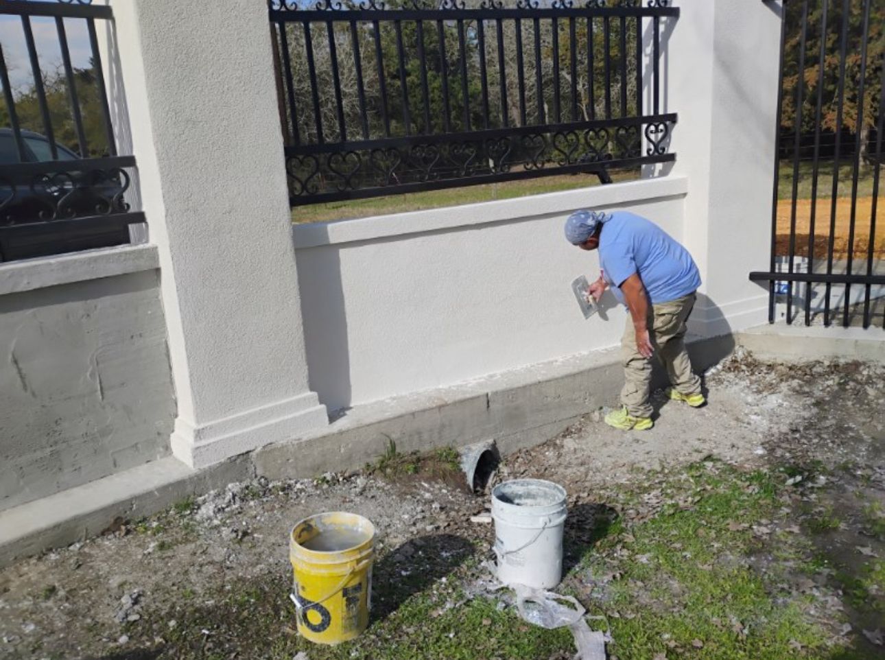 A man is painting a wall next to a yellow bucket with the letter b on it.