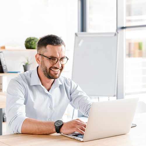 Um homem está sentado em uma mesa usando um laptop.