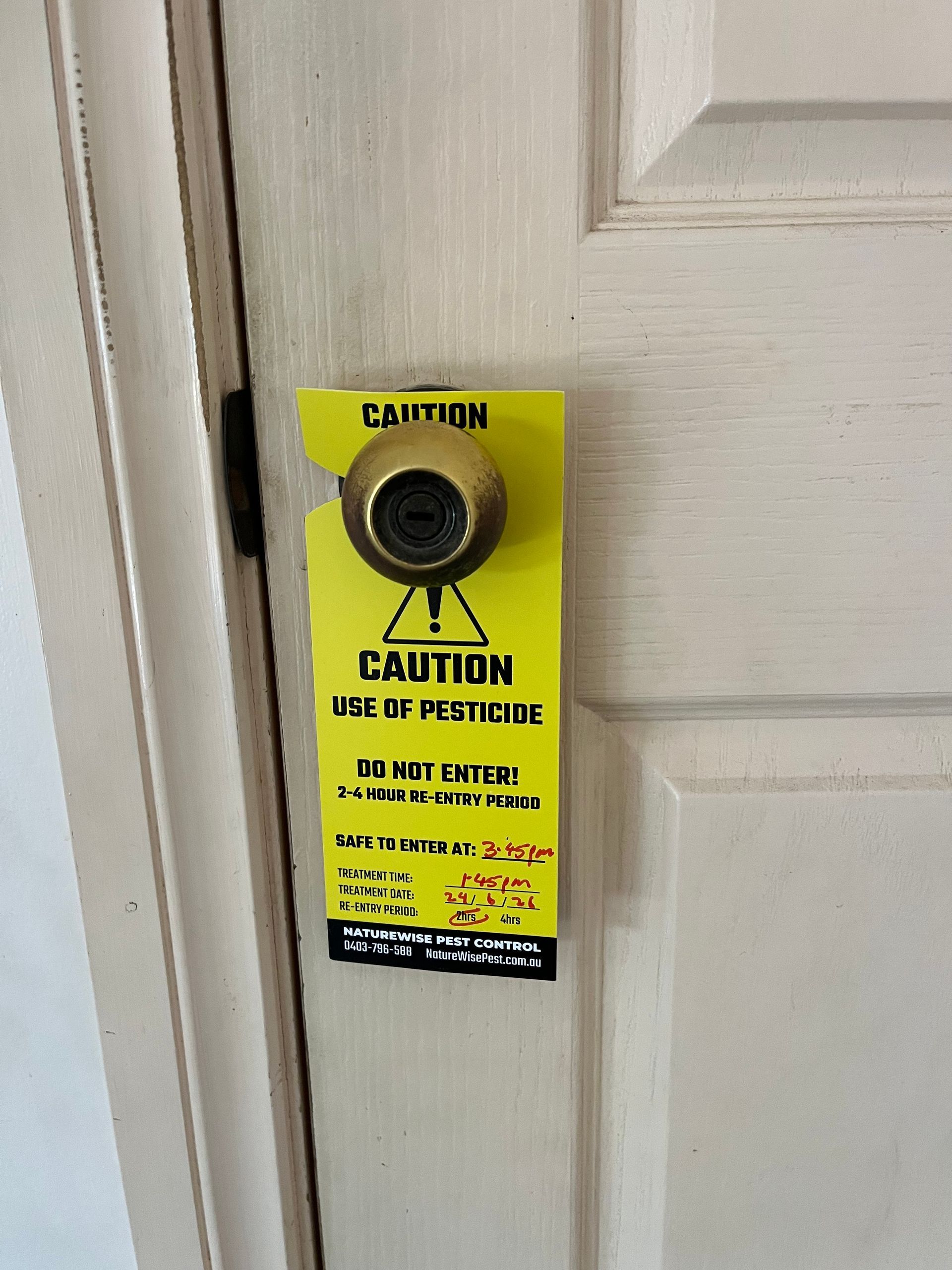 Yellow Caution Notice on a White Door Knob, Warning About the Door Latch — NatureWise Pest Control In Port Macquarie, NSW