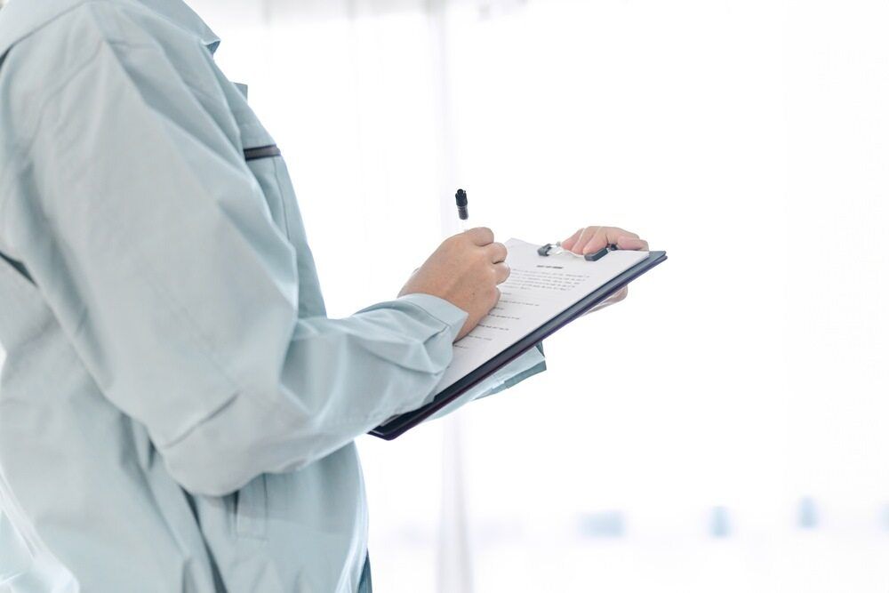 Person in Light Blue Workwear Writing on a Clipboard — NatureWise Pest Control In Port Macquarie, NSW