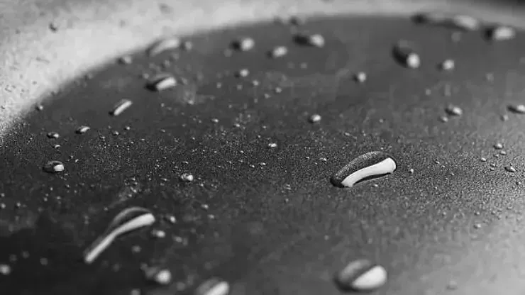 Close-up of a Dark Pan Surface With Water Droplets Scattered Across It — NatureWise Pest Control In Port Macquarie, NSW