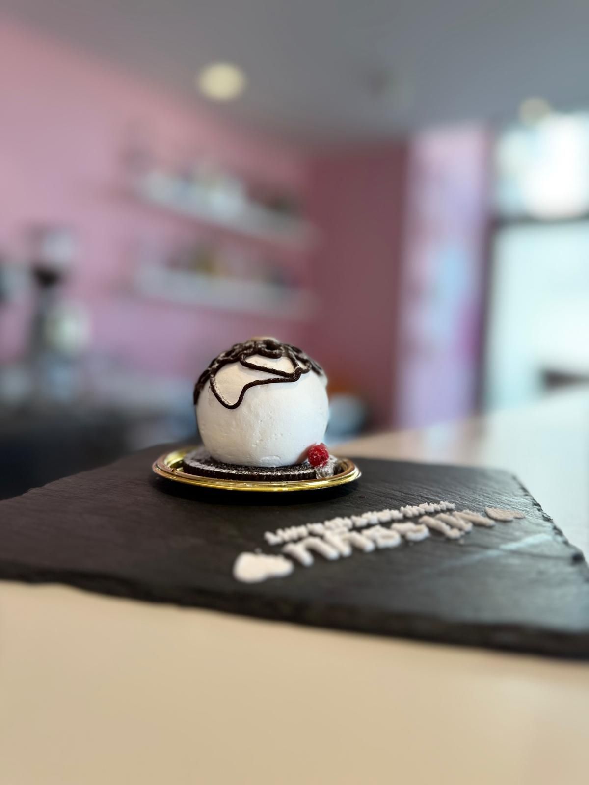 Dolce bianco con colata di cioccolato su un menu nero in un caffè dalle tonalità rosa