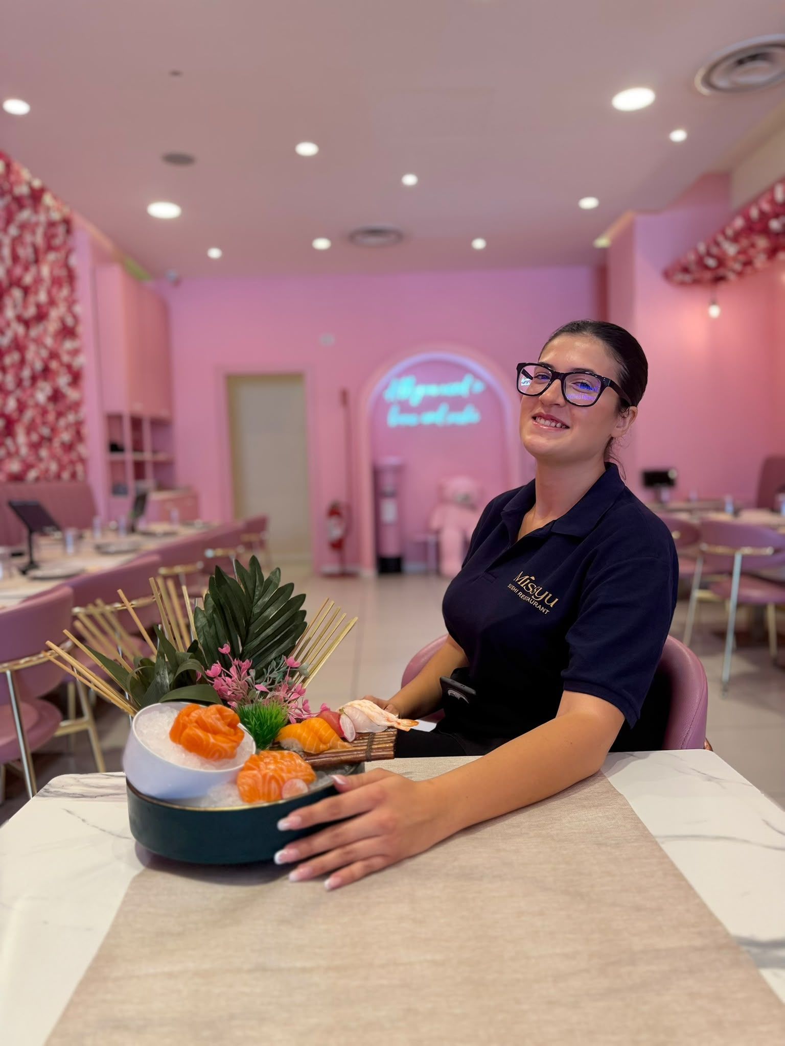 Donna in una sala per banchetti rosa che presenta un vassoio di sushi su un tavolo decorato