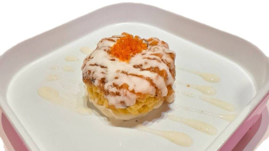 Dessert cremoso guarnito con arancia, servito su un piatto bianco con bordo rosa