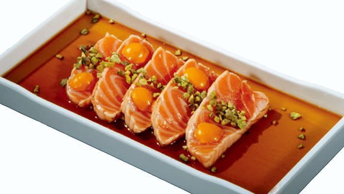 Sushi di salmone a fette disposti su un vassoio rettangolare con glassa all’arancia e guarnizione