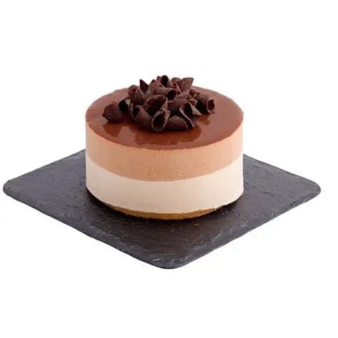 Torta al cioccolato con mousse su un piatto di ardesia nera, con scaglie di cioccolato in superficie