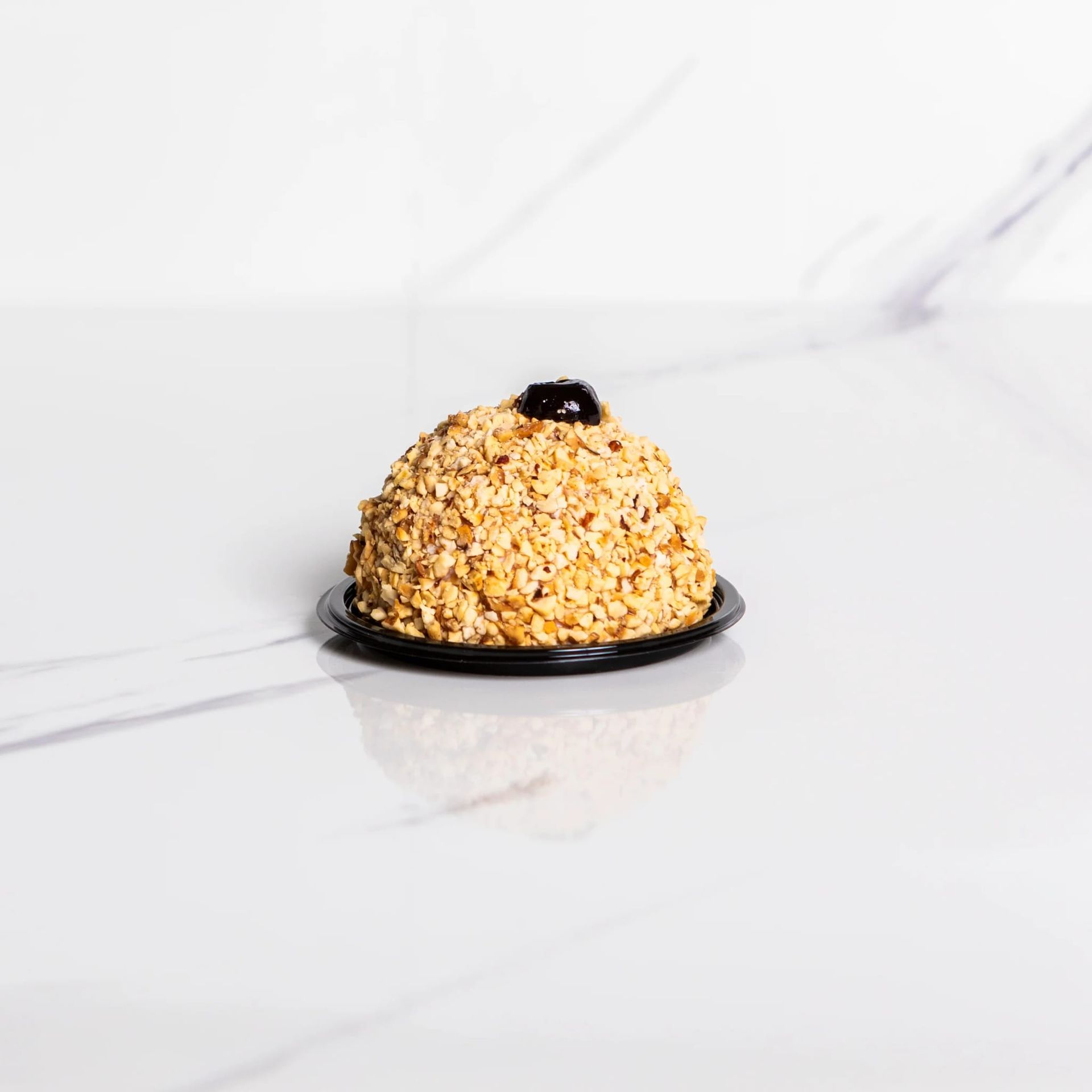 Dessert ricoperto d’oro su un piatto nero, su uno sfondo di marmo bianco