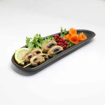 Sushi assortiti e guarnizioni su un vassoio nero, con limone, erbe aromatiche, funghi, bacche rosse e fiori di carota