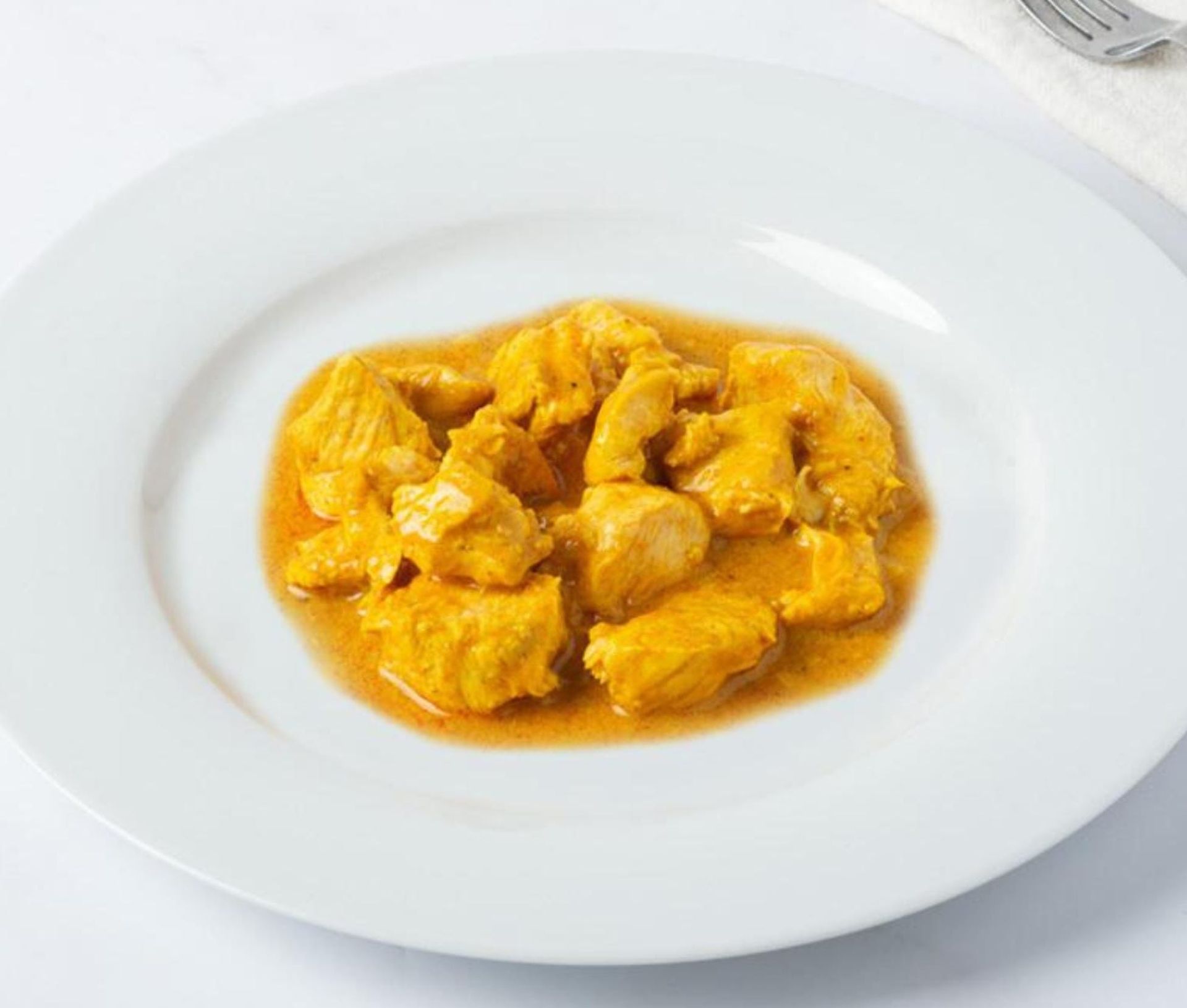Curry giallo servito al centro di un piatto bianco